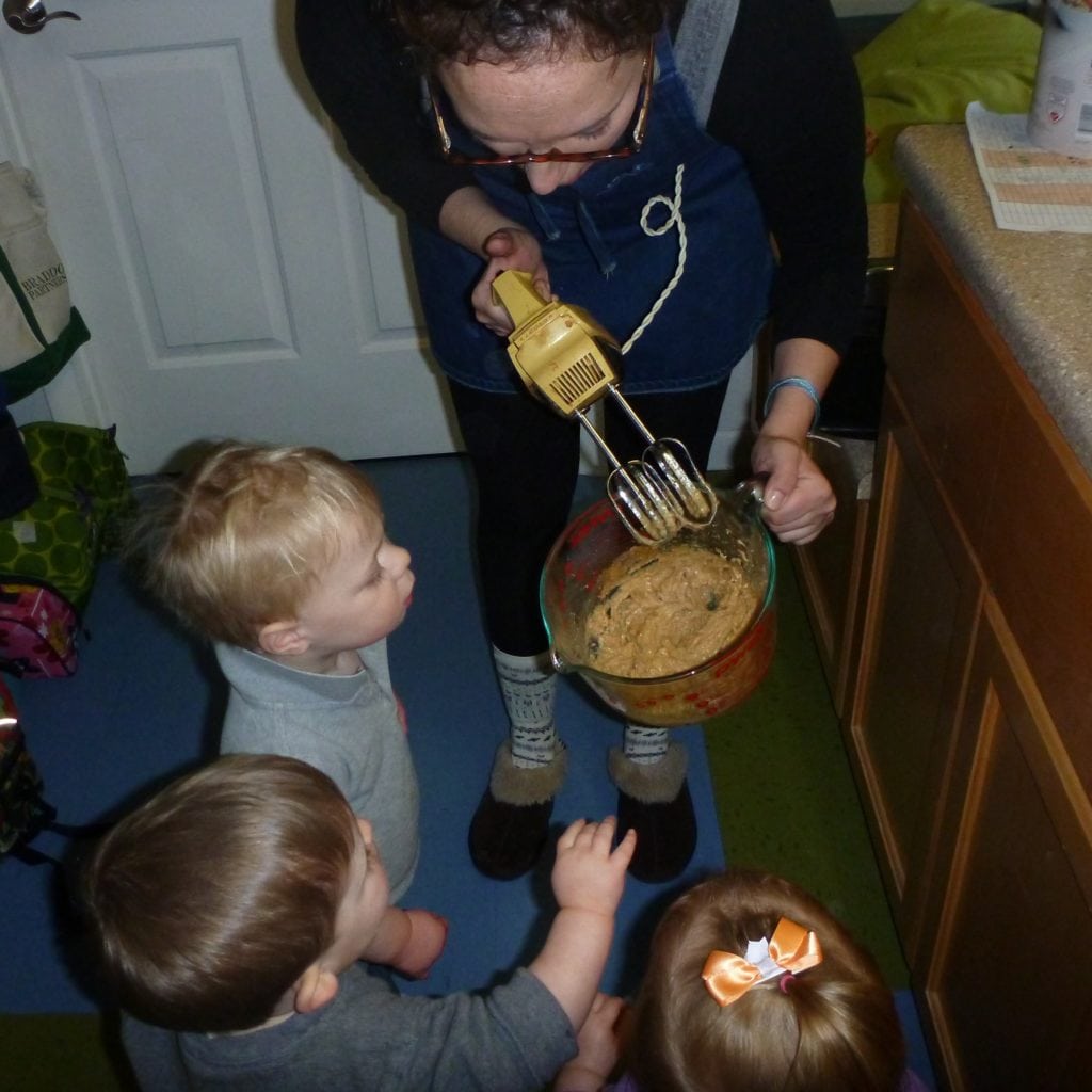 toddlers practice cooking with support from a teacher